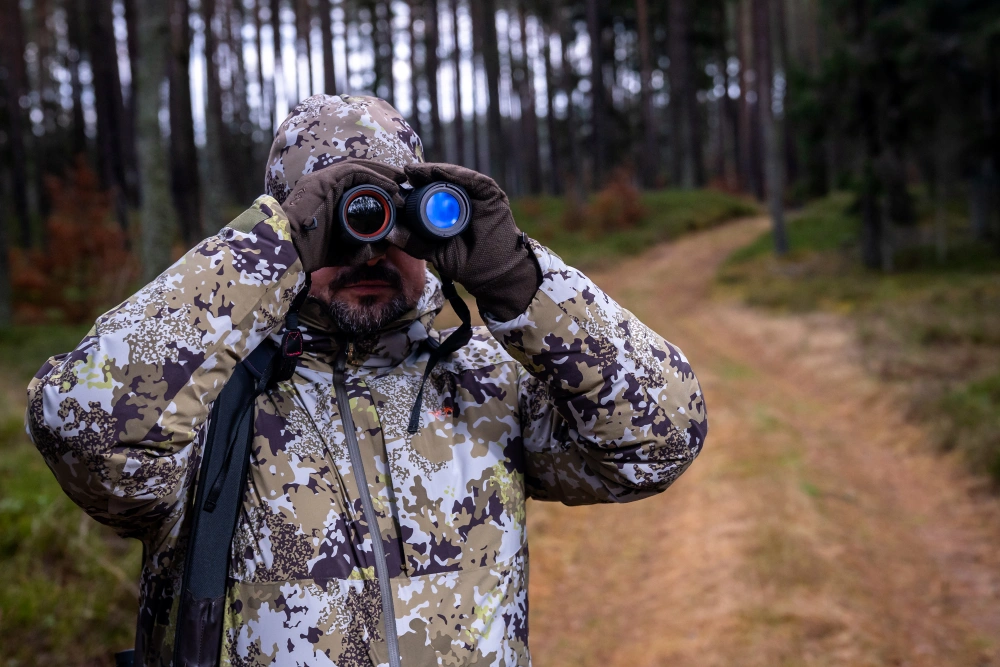 Ein Jaeger beobachtet bei Dunkelheit das Revier mit Waermebild oder Nachtsichtgeraet.