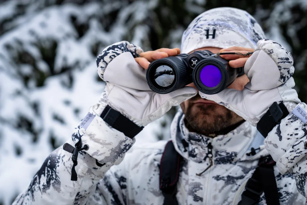 Jaeger beobachtet mit Waermebild Fernglas im Revier