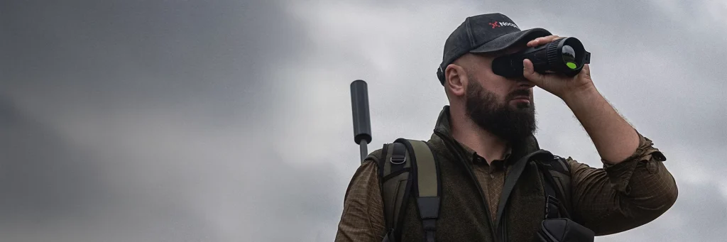 A man is looking through thermal imaging monocular outdoors.
