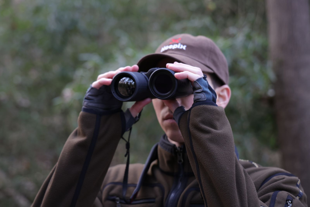 Jägare som använder kikare för att skanna skogen.