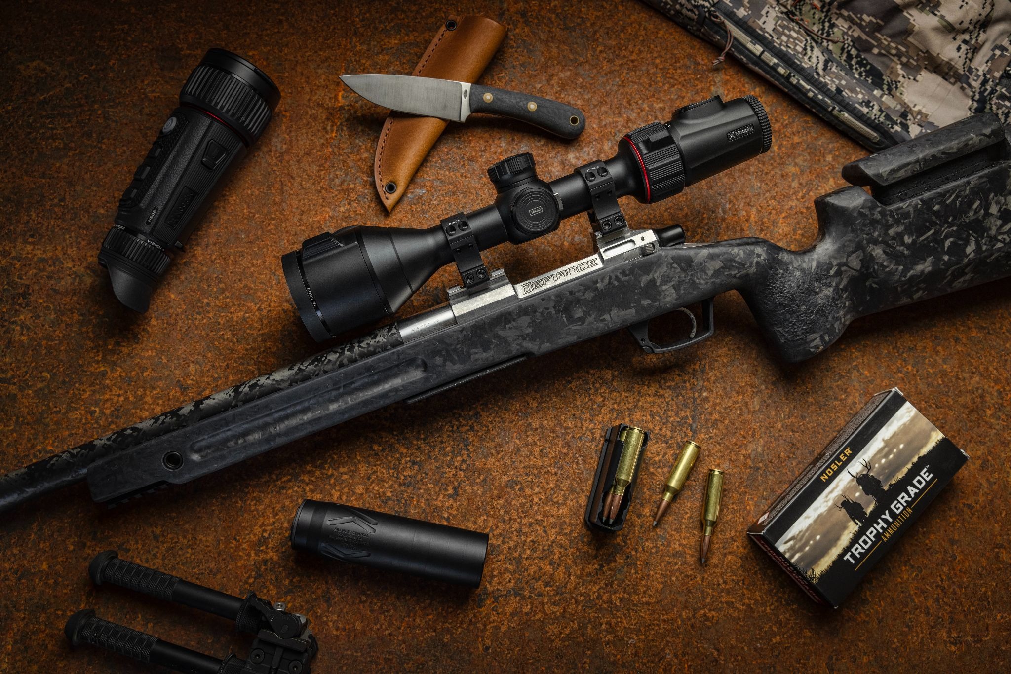 Thermal scope mounted on a rifle with hunting gear arranged on a table
