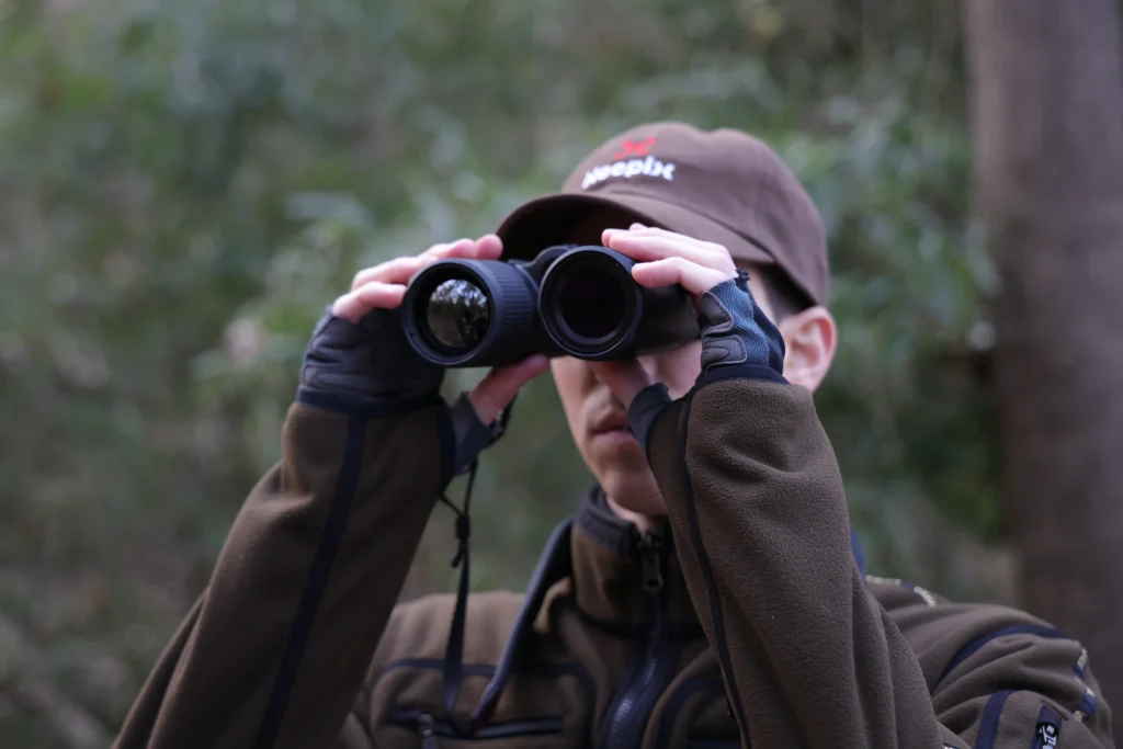Hunter scanning a forest using thermal binoculars